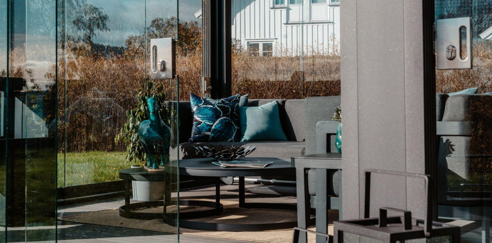 A glass door leads to a patio area featuring a couch and outdoor rugs, creating a cozy outdoor living space.
